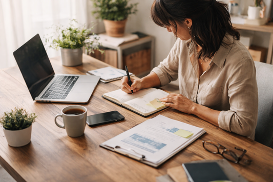 Small business owner organizing workflow and systems with laptop and planner on desk